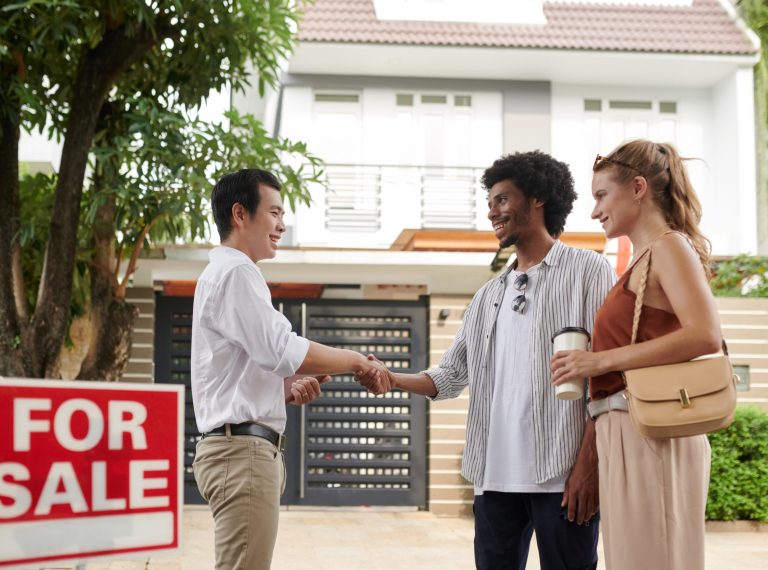 Positive diverse young couple greeting real estate agent in new district